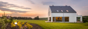 Large white house with gutter system in a field at sunset.