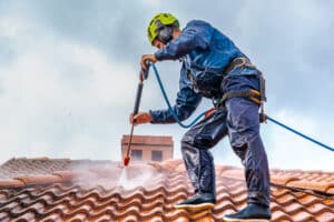 worker washing the roof with pressurized water