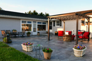 Stone paver patio in a backyard in the evening. Covered gazebo area with fire pit.