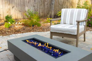 Electric fire place on a patio in a well-landscaped backyard.