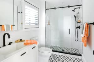 Modern remodeled bathroom with black and white color scheme and orange accents.