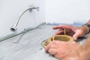 person fixing toilet flange in bathroom