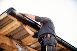 A man installs gutters on a roof.