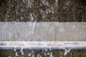 Water rushing over a model roof with a Raptor Gutter Guard.