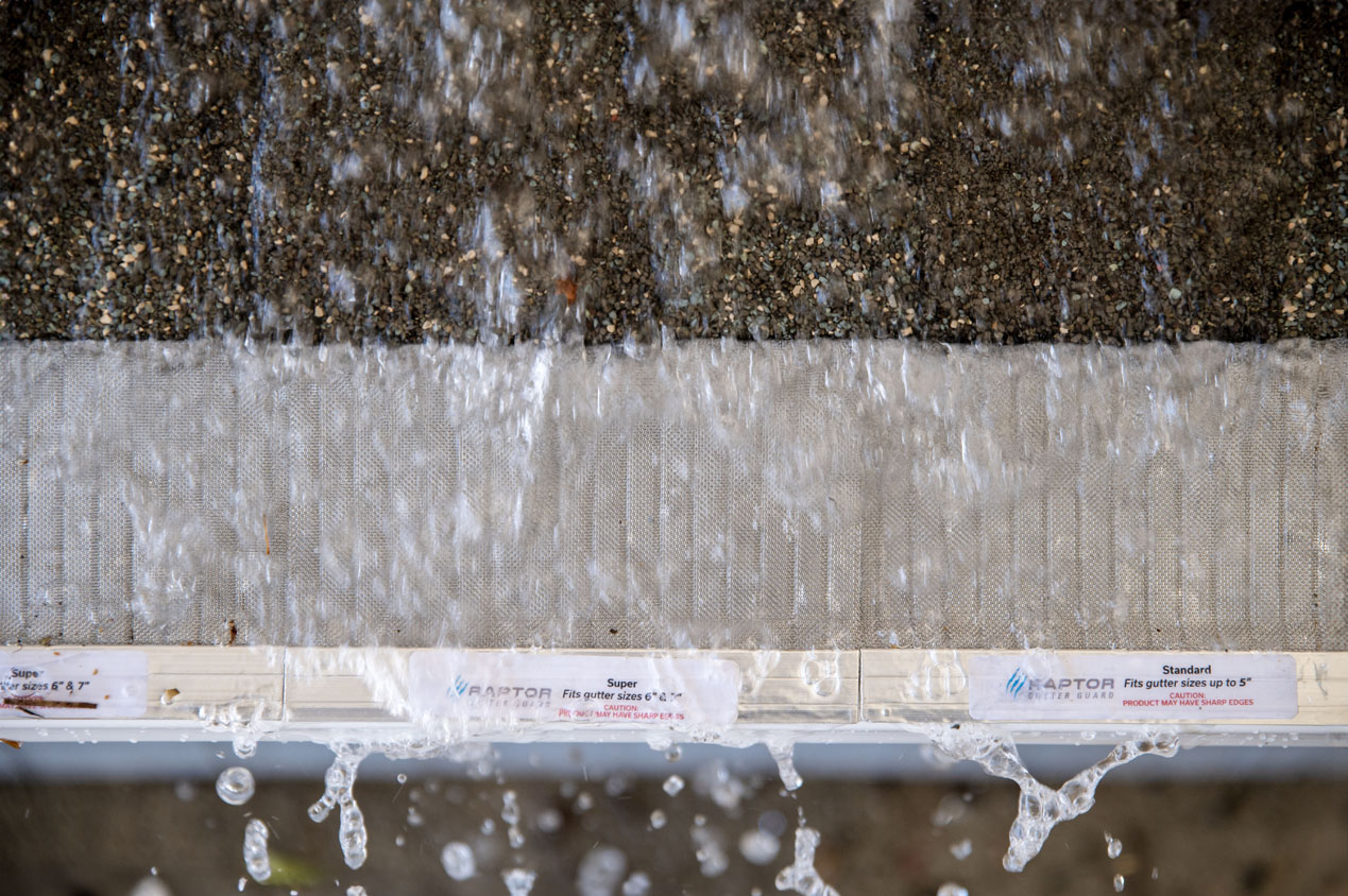 Water rushing over a model roof with a Raptor Gutter Guard.