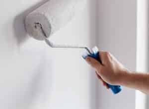 Male hand painting wall with paint roller