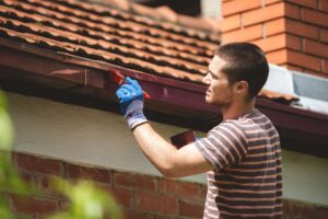 A man paints a gutter on a house