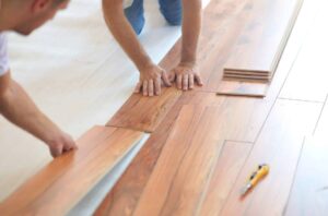 Itwo people installing new laminate flooring during a home remodel